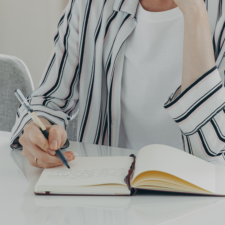person holding notepad and pen flat lay photography